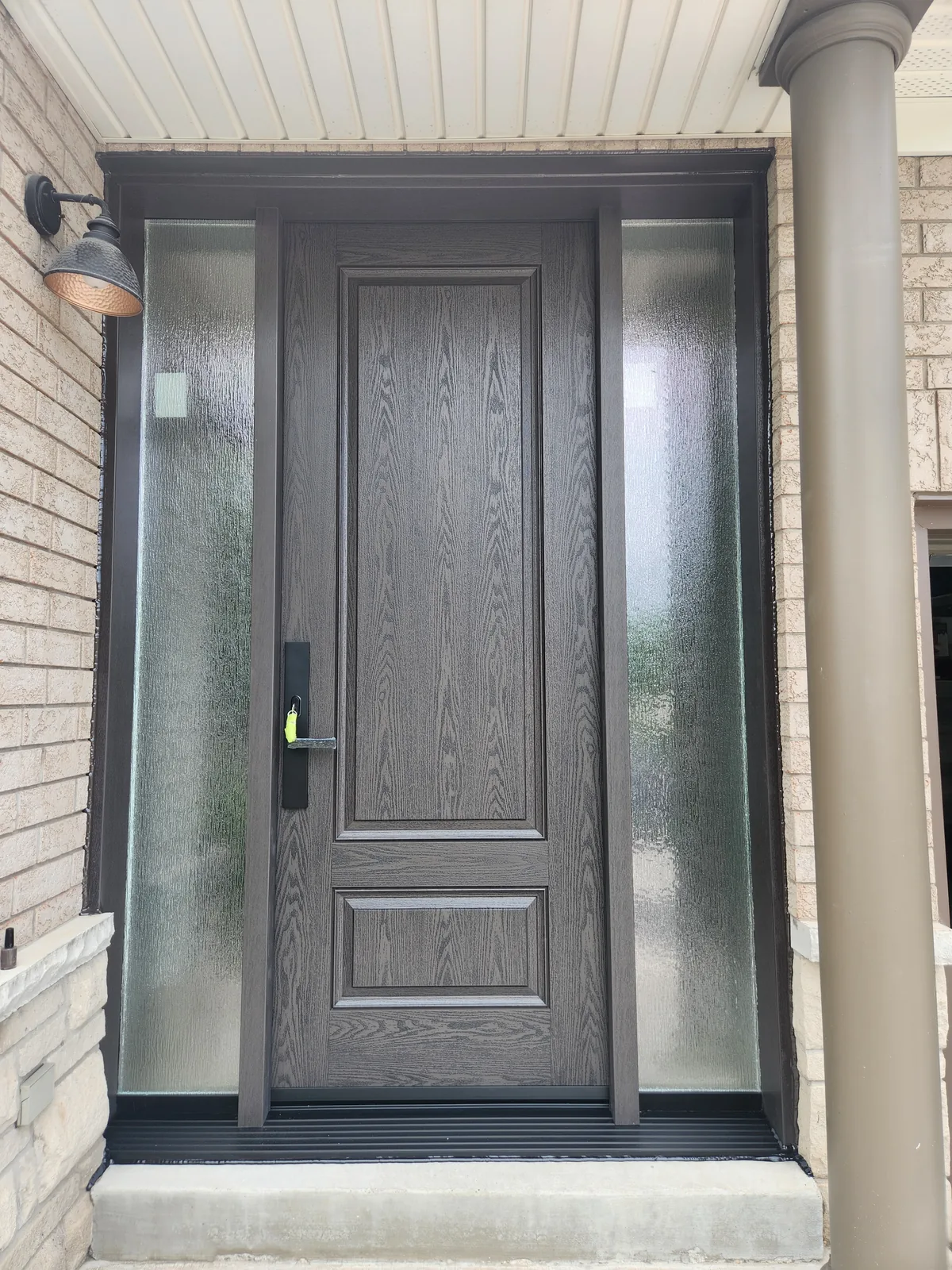 Woodgrain-textured fiberglass entry door with two full-height textured-glass sidelights in Guelph.