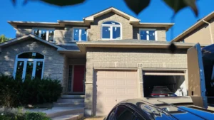 Hamilton brick and stone home with white vinyl replacement windows, including arched upper sections.