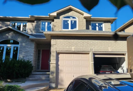 Hamilton brick and stone home with white vinyl replacement windows, including arched upper sections.