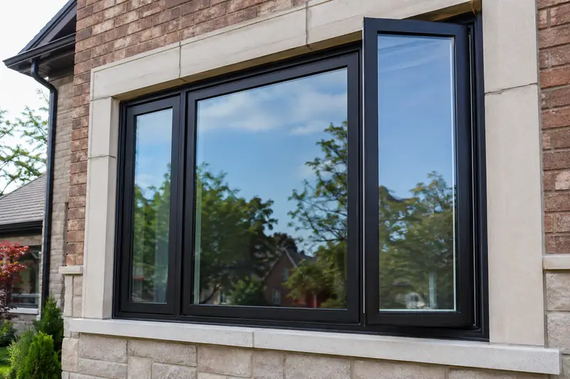 Black replacement window assembly in brick and limestone on a Hamilton home